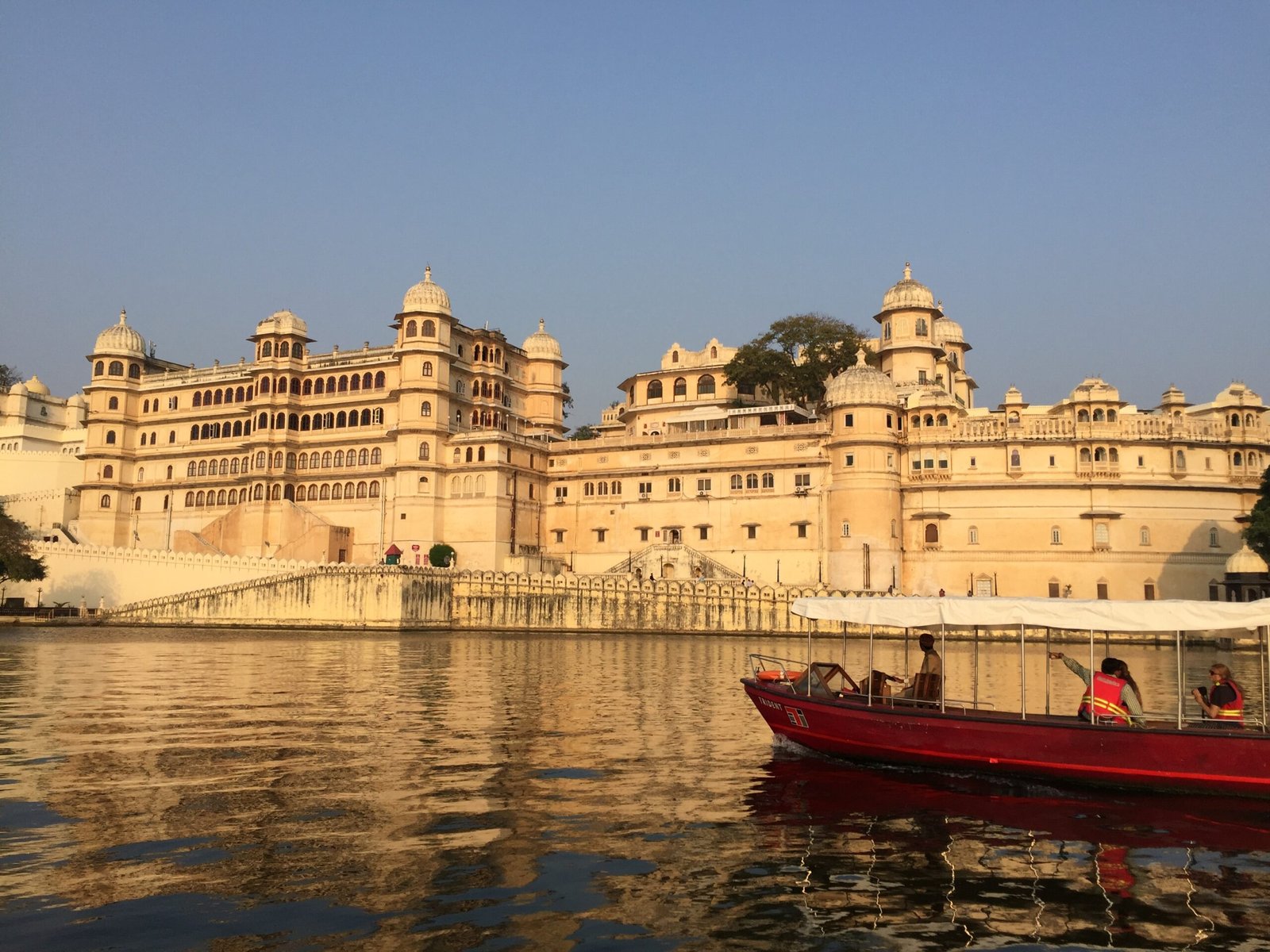 red and white boat on body of water near beige concrete building during daytime